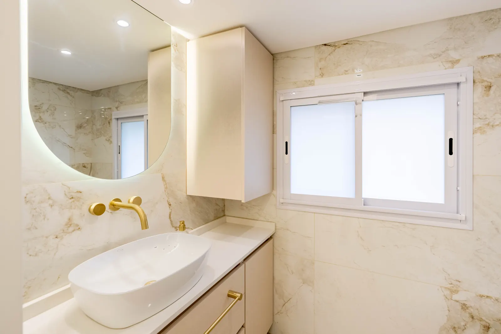 La bacha oval del baño privado con el espejo de aumento